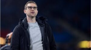 Per Mertesacker im Anzug blickt fokussiert, im Hintergrund das Logo des Deutschen Fußball-Bundes