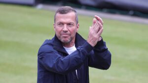 Lothar Matthäus als TV-Experte am Mikrofon vor der Kulisse eines Fußballstadions.