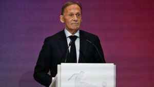 Hans-Joachim Watzke schaut ernst, im Hintergrund geht es um den Machtkampf zwischen UEFA und FIFA.