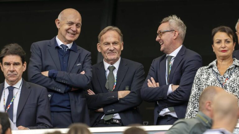 DFB-Aufsichtsrat Alexander Wehrle blickt ernst, im Hintergrund ist das Logo der FIFA zu sehen.