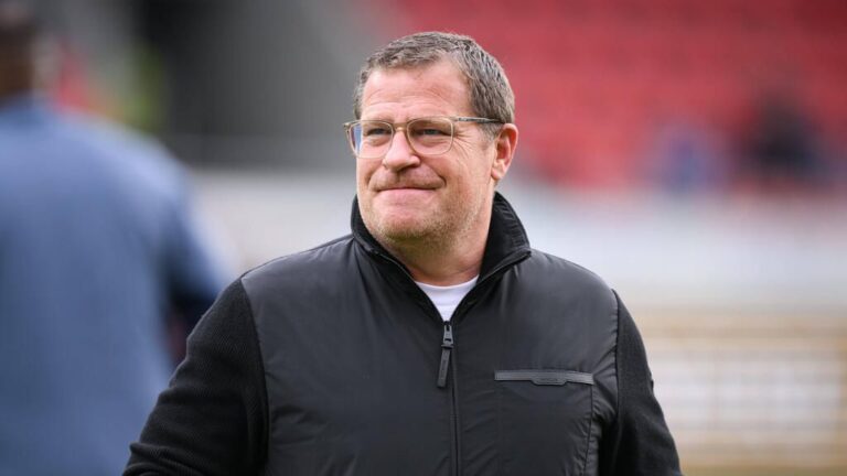 Max Eberl steht im Stadion des FC Bayern München und schaut konzentriert auf das Spielfeld.