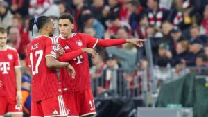 Jamal Musiala im Trikot des FC Bayern München blickt konzentriert auf das Spielfeld.