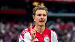 Mika Godts im Trikot von Ajax Amsterdam und Torhüter Zion Suzuki von Parma Calcio auf dem Platz.