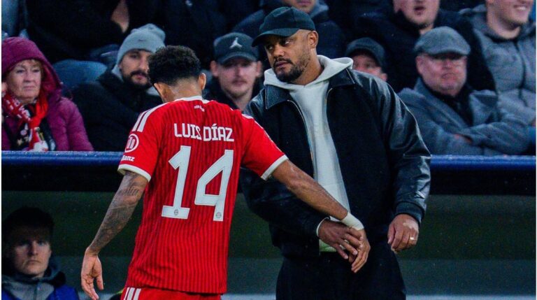 Bayern-Trainer Vincent Kompany blickt nachdenklich, während ein medizinischer Betreuer auf dem Platz steht.