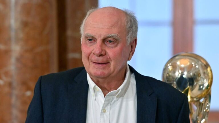 Uli Hoeneß und Jonas Urbig vor dem Vereinswappen des FC Bayern München
